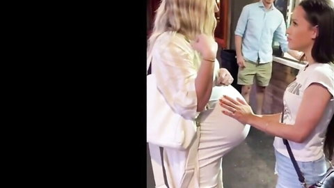 Pregnant Lauren in white dress as Arie touches her belly in lesbian scene