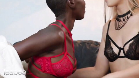 Ebony babe in red lace bra with exposed tits leans close to blonde model in black lingerie showing medium tits