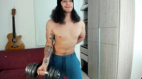 Shirtless muscular tattooed brunette hunk with long hair lifts dumbbell in blue sweatpants webcam tease