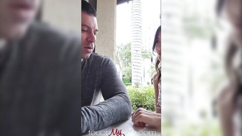 Brunette hotwife in white top smiles with husband at outdoor table