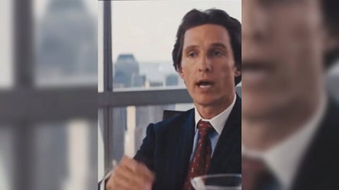 Suited man gesturing passionately while speaking at table with city skyline view