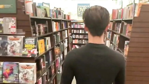 Robbie Dash browsing DVDs in bookstore aisle, gay adult scene