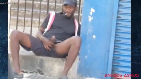 Black guy pulls down shorts to stroke his thick erect cock outdoors on blue wall steps