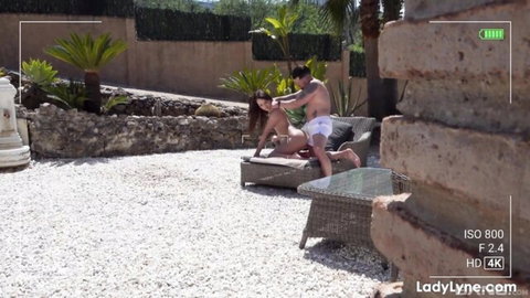 Curvy brunette with huge tits topless on outdoor couch as shirtless hunk massages her hair