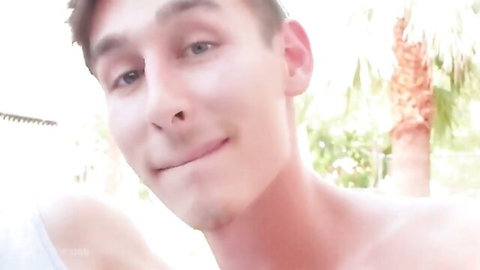 Shirtless handsome twink smirks seductively outdoors by pool with palm trees