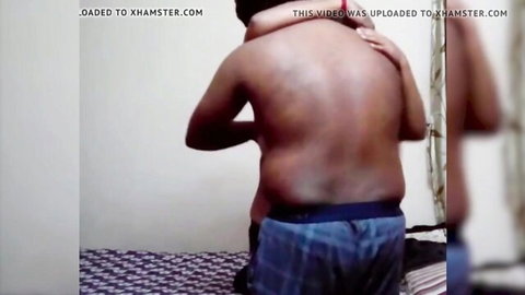 Shirtless South Asian man in boxers hugs mature woman from behind on bed