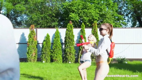 Blonde and redhead teens in sexy shorts squirting water guns outdoors, summer fun turns horny