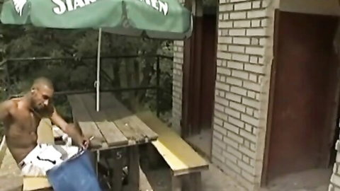 Shirtless Black man outdoors holding bag in amateur voyeur punishment scene