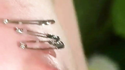 Close-up of sharp metal pins piercing tender red skin in bizarre fetish scene