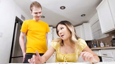 Surprised Asian blonde MILF in yellow top gestures at stepson in kitchen tease