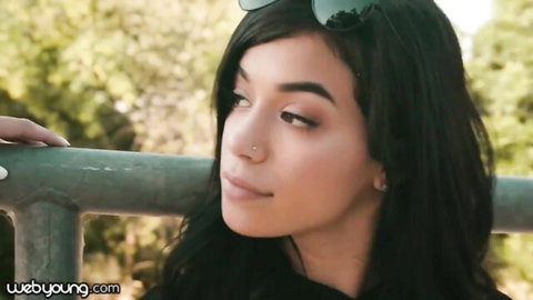 Seductive Latina skater girl with long black hair and sunglasses outdoors