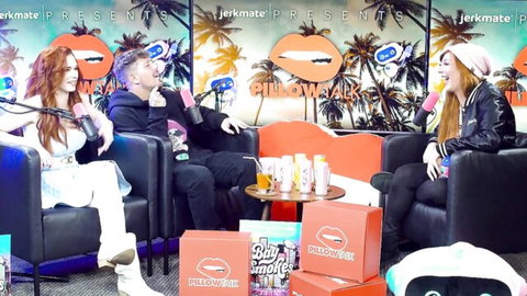 Curvy redhead in tight white pants interviewed on Jerkmate Pillow Talk with host and blonde babe