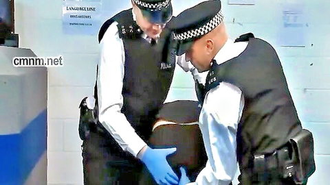 Female cop in gloves fingers bent-over male suspect in uniform roleplay