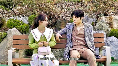 Clothed Asian couple sitting closely on wooden bench outdoors talking intimately