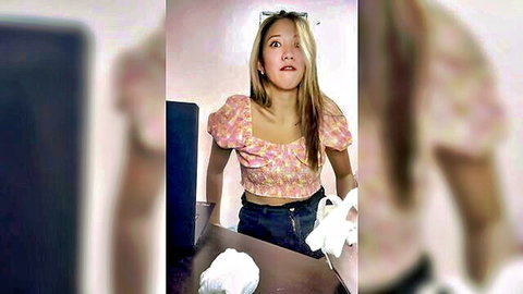 Cute Asian amateur in pink floral top and jeans holding white socks with surprised O-mouth