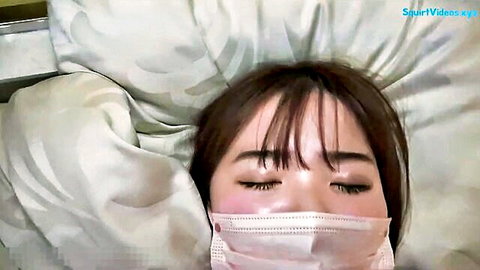 Sensual Asian brunette babe with surgical mask lying relaxed on bed eyes closed