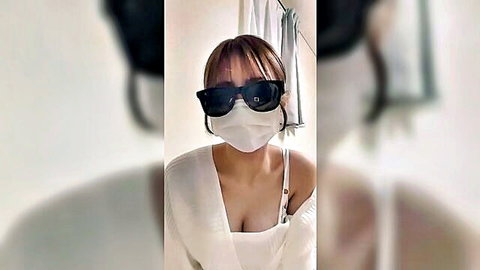 Asian woman in sunglasses and mask, off-shoulder top showing cleavage tease