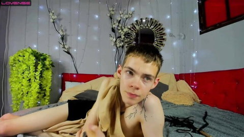 Shirtless twink boy teases on webcam bed draped in towel showing toned abs and tattoo