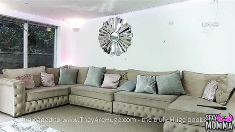 Modern living room with plush beige tufted corner sofa, gray and pink pillows, and large starburst mirror