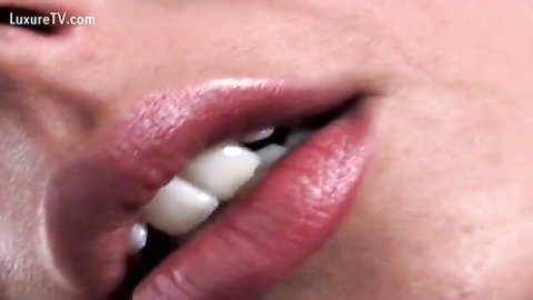 Close-up of woman's glossy red lips and teeth in BDSM fetish teaser