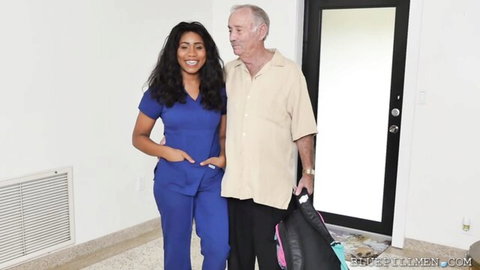 Young smiling nurse in blue scrubs with older man at home door