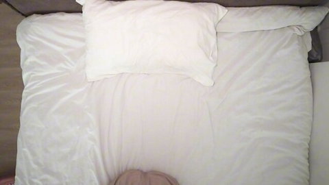 POV closeup of woman writhing on white sheets in bed ecstasy