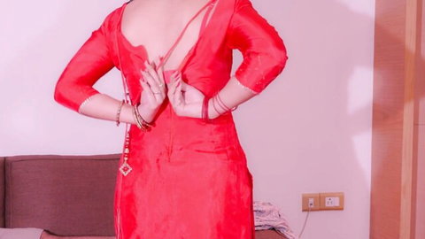 Indian stepmom in sexy red backless dress, hands clasped behind back