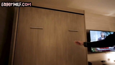 MILF hotel room with open murphy bed, TV on, man's arm reaching in eagerMILF scene