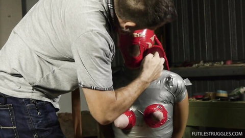 Diamondly bound in tape, gagged by captor in experimental bondage scene
