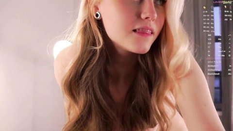 Seductive blonde webcam girl pouts plump lips close-up with bare shoulders solo tease
