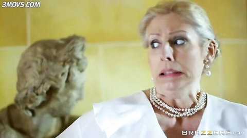 Erica Fontes shocked in elegant white dress and pearls, blonde updo