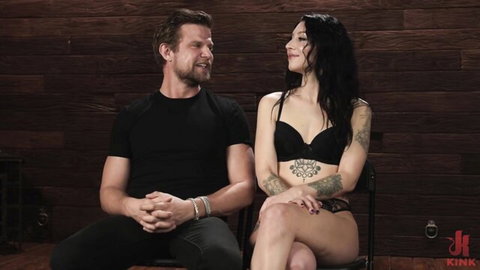 Raven Lane in black lingerie with tattooed arms and muscular man in kinky couple scene