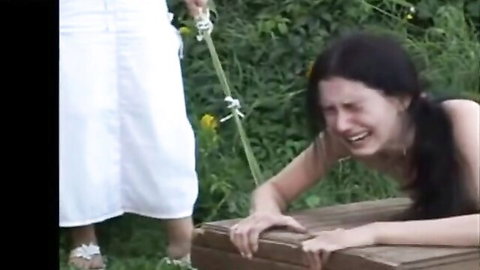 Naked brunette leashed and crying on all fours, punished by dominant woman in blue dress