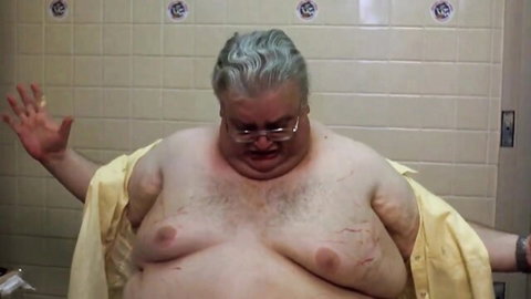 Chubby older white man in open yellow robe, exposed hairy belly, surprised in bathroom