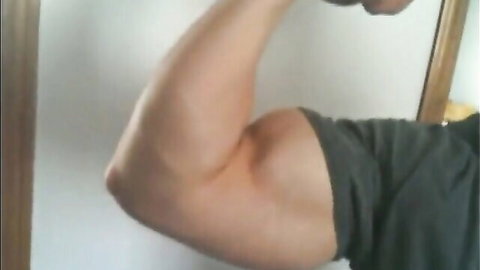 Muscular man flexing bicep in mirror, showcasing strong arm