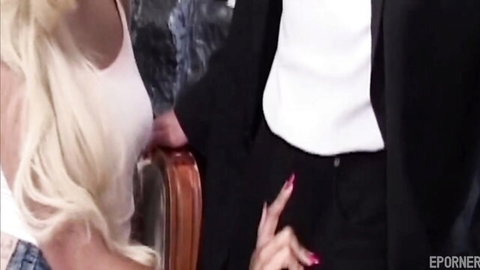 Blonde woman in white tank top eagerly reaching for suited man's crotch
