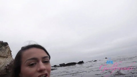 Brunette Calibunny smiles seductively in beach selfie with rocky ocean backdrop