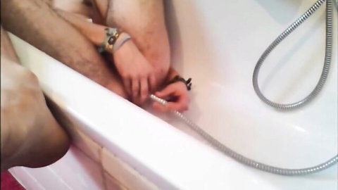 Hand fingering tight gay asshole in bathtub with shower hose for enema play