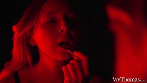Valeria Mint applying red lipstick in mirror, seductive blonde gaze