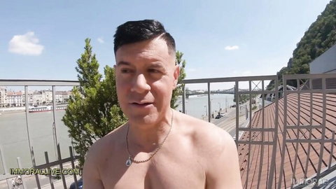Shirtless man on sunny balcony overlooking river in Stacy Cruz stepmom passion