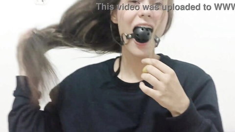 Brunette with black ball gag in mouth teasing while wearing tight black sweater