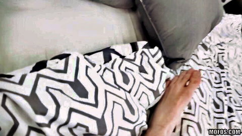 Close-up of woman's bare leg and foot on patterned bed sheets in kinky anal setup