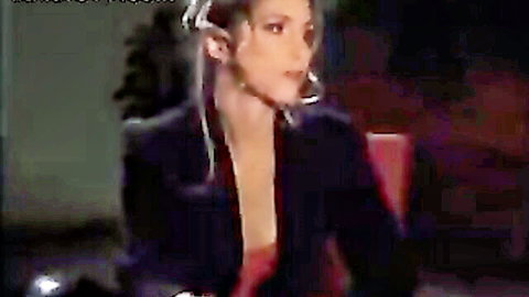 Blonde woman in open black blazer showing cleavage with headset, Elite Pain club scene
