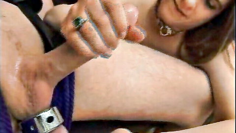 Femdom mistress with choker and green nails holds locked chastity cage on hairy man's exposed cock