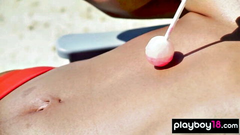 Topless Asian big-boobed babe sunbathing on beach with lollipop