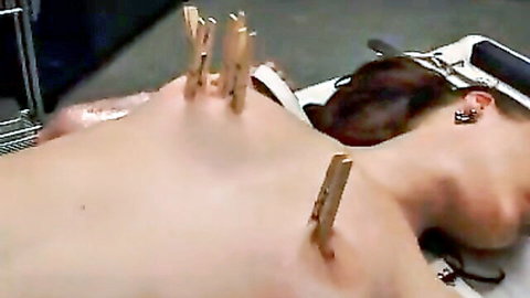 Christine nude on table, clothespins on back in BDSM torture scene