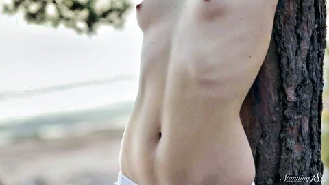 Sasha Green topless striptease at sunset, slim nude body against tree