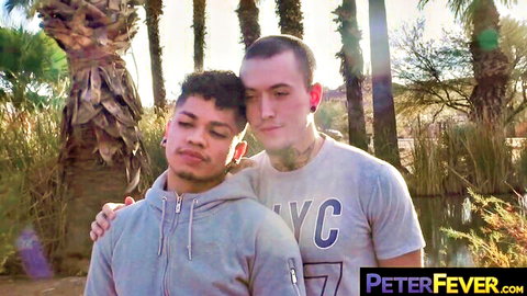 Tyler Slater and Angel Salvador cuddling outdoors, Tyler in hoodie hugging Angel in t-shirt