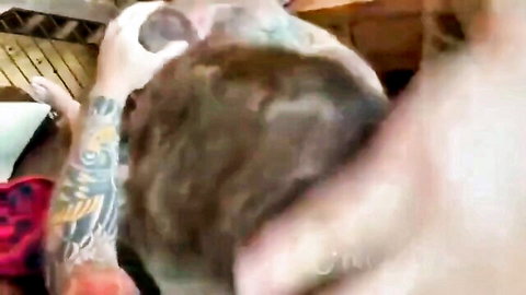 Tattooed hands gripping young man's head in explicit oral sex scene