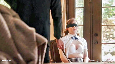 Blindfolded schoolgirl in bra and skirt, older man in suit behind her